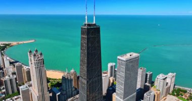 Chicago 'daki Michigan Gölü' nün inanılmaz güzellikteki göl manzarasının arka planında John Hancock Center kulesi. İHA görüntülerinden gökdelenin tepesindeki antenlere yaklaşıyoruz..