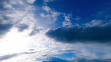 Gri bulutlar güneşi gölgeliyor. Mavi gökyüzü dramatik bulutlarla kaplıdır. Düşük açı. Zaman Uygulaması.