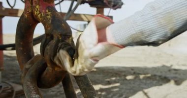 Büyük metal cevizi sıkan koruyucu eldiven giyen bir işçinin eli. Petrol ve gaz sondajı için ekipman ayarlanıyor. Kapat..