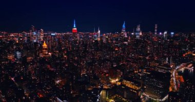 Gökdelenlerin tepeleri neon ışıklarıyla aydınlatılmış şehir panoramasından dışarı çıkıyorlar. Geceleri New York, ABD 'de hava perspektifi.