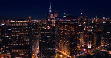 Geceleri çok katlı binalardaki ışıklı pencereler. Akşamları New York, ABD 'nin mimarisi yakınlarında insansız hava aracı uçuşu.