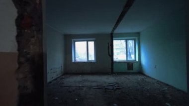 Boş odayı iki pencereyle beyaza boyamak. Koridorda enkaz ya da inşaat malzemesi transferi için iki itme arabası var..