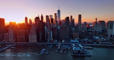 Parlak güneş, gün batımında muhteşem Manhattan, New York 'un siluetinin arkasında saklanıyor. İHA görüntüleri Doğu Nehri üzerinde uçuyor..