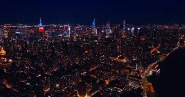 New York, ABD 'nin ışıltılı manzarasında gökdelenlerin neon tepeleri göze çarpar. İnsansız hava aracı görüntüleri Metropolis 'in gece manzarasının üstünde..