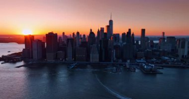 Parlak turuncu güneş Manhattan 'daki en yüksek gökdelenlerin tepelerini aydınlatıyor. Pembe gökyüzü New York manzarasının üzerinde altın saatinde.