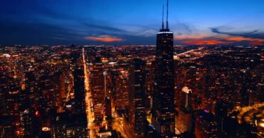 Muhteşem Chicago, Illinois, ABD 'de ışıl ışıl bir gece. Ufukta turuncu gökyüzüyle çarpıcı bir şekilde aydınlatılmış şehrin üstündeki insansız hava aracı görüntüleri..