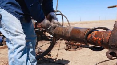 Kirli eldivenli tanınmayan adam borudaki parçaları söker. Petrol ve gaz sondajı için gerekli ekipmanı sağlayan işçiler.