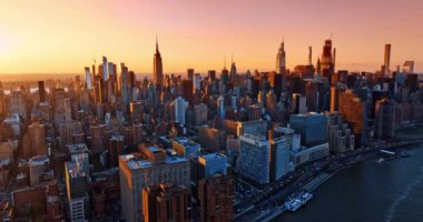 Gün batımının turuncu ışığında New York mimarisinin muhteşem manzarası. Metropolün üstündeki pembe-turuncu gökyüzü. Üst perspektif.
