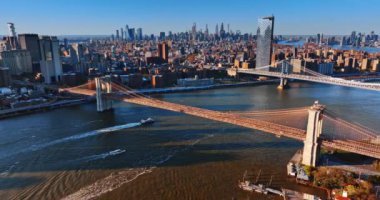 Günbatımında Manhattan Köprüsü ve Brooklyn Köprüsü olan Doğu Nehri. Köprülerin altında iki tekne su üzerinde yüzüyor. Üst görünüm.
