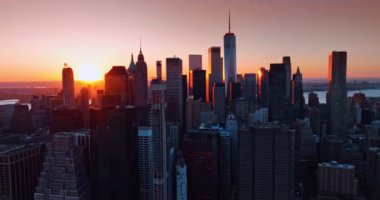 Manhattan 'ın yüksek binaları ufuk çizgisini kaplıyor. New York 'ta güneş batıyor, ABD mimariyi turuncu ışıkla aydınlatıyor. Üst görünüm.