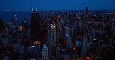 Metropolis 'e gece çöküyor. Muhteşem Chicago binalarda ve caddelerde ışık değiştiriyor. İHA şehir panoramasının üzerine iniyor..