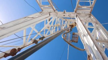 Döndürme çubuğu beyaz metal kuleye bağlı. Açık havada çalışan sondaj ekipmanlarının düşük açılı görüntüsü.