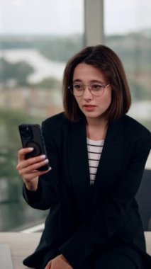 Gözlüklü genç bayan telefonda konuşuyor. Esmer kız internet pandomimcisi ve el kol hareketi ile iletişim kuruyor. Dikey video.