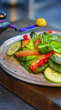 Sebze salatası, greyfurt ve salata yapraklı tabak. Aşçı bir parça sarı domates koyar. Sağlıklı yemek servisi. Kapatın. Dikey video.