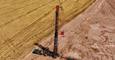 Doğal kaynakları delmek için ekinlerin yetiştiği güneşli bir arazi. Petrol üretimi için araçların ve ekipmanların üstündeki İHA görüntüleri.