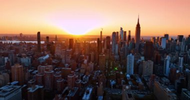 Günümüz New York şehrinde güneş ufukta batıyor. Şehir merkezindeki turuncu gökyüzünün altında yapılan insansız hava aracı görüntüleri..