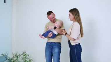 Babasının ellerinde, çıplak ayaklı, sevimli bir çocuk. Anne çocuğun ellerini onun ağzından uzak tutar..