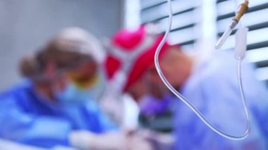 Serumdan tüp takılmış bir kapak iğnesi. Kapatın. Doktor ve hemşire arka planda çalışıyor..