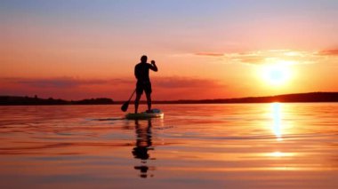 Meditasyon için güzel bir yer ve zaman. Adam gün batımında nehrin kıyısında süzülüyor. Düşük açı görünümü.