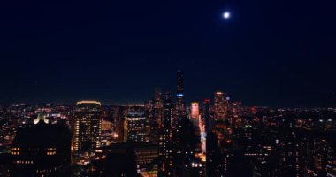 Geceleri New York 'un uçsuz bucaksız şehrinin üzerinde. Ay metropolün üstünde, mavi gökyüzünde..