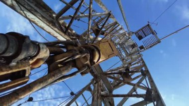 Kalın metal kablolarda asılı duran matkap ekipmanları işten titreşiyor. Petrol üretimi için derenin düşük açılı görüntüsü.