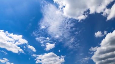 Küçük tüylü beyaz bulutlar gök kubbede hareket ediyor. Parlak yaz gökyüzü ile aydınlatılan güzel bulutlara alçak açı. Zaman Uygulaması.