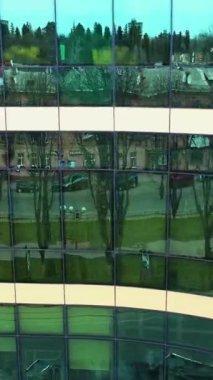Gökdelen binasının pencereleri. Camdan pencereleri ve yansıması olan modern ofis gökdelenleri. Dikey video