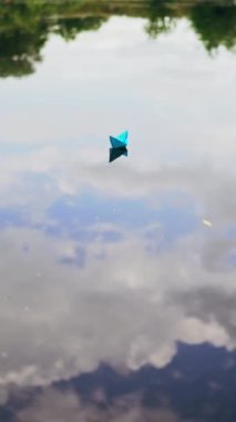 Nehirde kağıt tekne. Nehir boyunca yüzen kağıt tekne. Dikey video