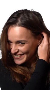 Gülümseyen, saçları tarayan tatlı kız. Güzel, uzun saçlarını tarayan bir kadın, beyaz arka planda izole edilmiş. Dikey video