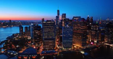 Alacakaranlıkta Manhattan, New York 'un çeşitli binalarına yaklaşıyoruz. Şehir manzarası yukarıdan pembe gökyüzü arkaplanda.
