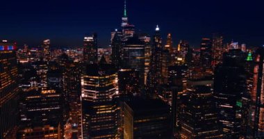 Modern, hareketli kentteki yüksek binaların tepeleri. Geceleri New York gökdelenlerinin tepesinde neon ışıklar yanar..