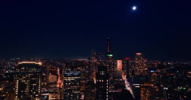 Ay, New York şehrinin üzerindeki koyu mavi gökyüzünde parlıyor. Gece aydınlık şehre havadan bir bakış açısı.