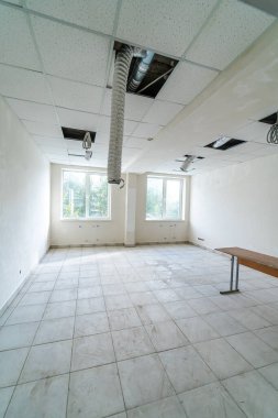 Hasarlı tavanı ve gündüz doğal ışığı olan boş bir ofis. Boş bir ofiste hasarlı bir tavan ve açık eşyalar bulunur.