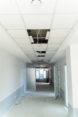 Açık tavan elementleri olan ticari bir koridorun yenilenmesi. Açığa çıkmış tavan panelleri ve elektrik kablolarıyla devam eden yenileme çalışmaları