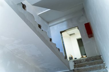 Modern bir binada yapım aşamasında olan merdiven, tamamlanmamış bir binayla çevrili modern bir binaya çıkıyor.