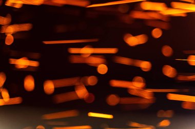 Parlayan kıvılcımlar ve karanlık bir ortamda yakalanan parlayan parçacıklar. Kıvılcımlar ve parıldayan parçacıklar havada dans ederek karanlık bir ortamda büyüleyici bir etki yaratır.