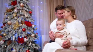 Küçük bebekleriyle kanepede oturan beyaz bir çift. Noel 'de evde mutlu bir beyaz ailenin portresi. Düşük açı görünümü.