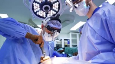 Cerrahi loplardaki beyin cerrahı ameliyatta tornavida kullanıyor. Tıbbi ekip ameliyathanede çalışıyor. Düşük açı görünümü.