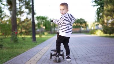 Beyaz erkek çocuk mobiletini sürerken kameradan uzaklaşıyor. Yürüyen çocuk yürüyüş sırasında aktif olarak vakit geçiriyor. Düşük açı. Dikey video.