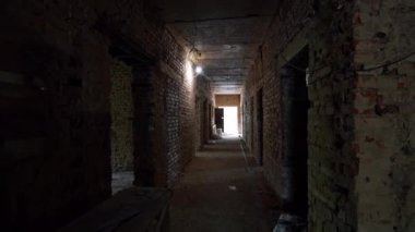 Duvarları tuğlalı eski binadaki uzun koridorda ilerliyorlar. İç mimari malzemeler koridorda..
