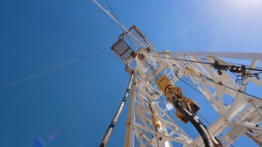 Yüksek metal korkuluklara bağlı çalışan bir işçi. Petrol üretim endüstrisindeki ekipmanlar. Düşük açı görünümü.