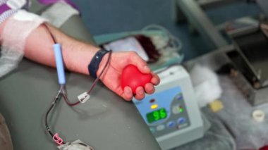 Erkek bir donörün elindeki küçük kırmızı plastik kalp. Kateter kanla dolu. Kan nakli ve kan bağışı.