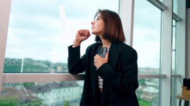 Düşünceli Kafkasyalı esmer pencereye bakıyor. İş kadınının elinde telefon var ve aramasını bekliyor. Düşük açı görünümü.