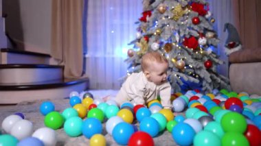 Küçük bebek, Noel ağacının yanında yere saçılmış çoklu topların yanında emekliyor. Çocuk bir top seçiyor ve ağzına çekiyor. Kara kedi arka planda belirir.