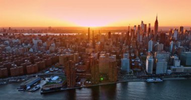Günbatımında Doğu Nehri üzerinde uçuş. Batan güneşin turuncu ışığında muhteşem New York manzarası.