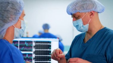Erkek cerrah bayan meslektaşıyla konuşur. Doktorlar sinir cerrahisinin ilerlemesini tartışıyor. Kapat..