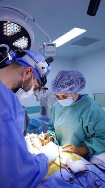 Çeşitli meslektaşlar beyin cerrahisinde çalışıyor. Doktorlar prosedürde tıbbi aletler kullanırlar. Dikey video.