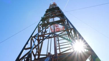 Güneş ışınları metal kule direklerinden geçer. Petrol üretimi için derenin alçak açılı görüntüsü.