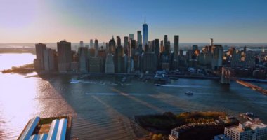 Manhattan binaları Doğu Nehri 'nin sularına uzun gölgeler saçar. Nehirde birkaç tekne var. Gün batımında metropolde hava perspektifi.