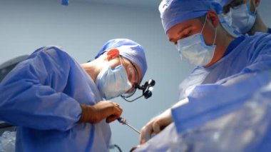 İki beyin cerrahı hastanede ameliyat yapıyor. Cerrahi hoparlör takan ve metal alet kullanan doktora düşük açılı bakış açısı.